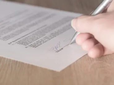 A picture of someone signing a contract with a pen