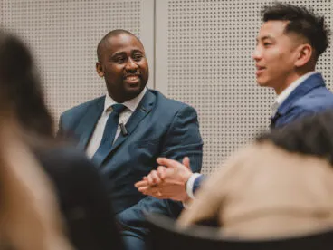 Two people smiling and talking within a group.